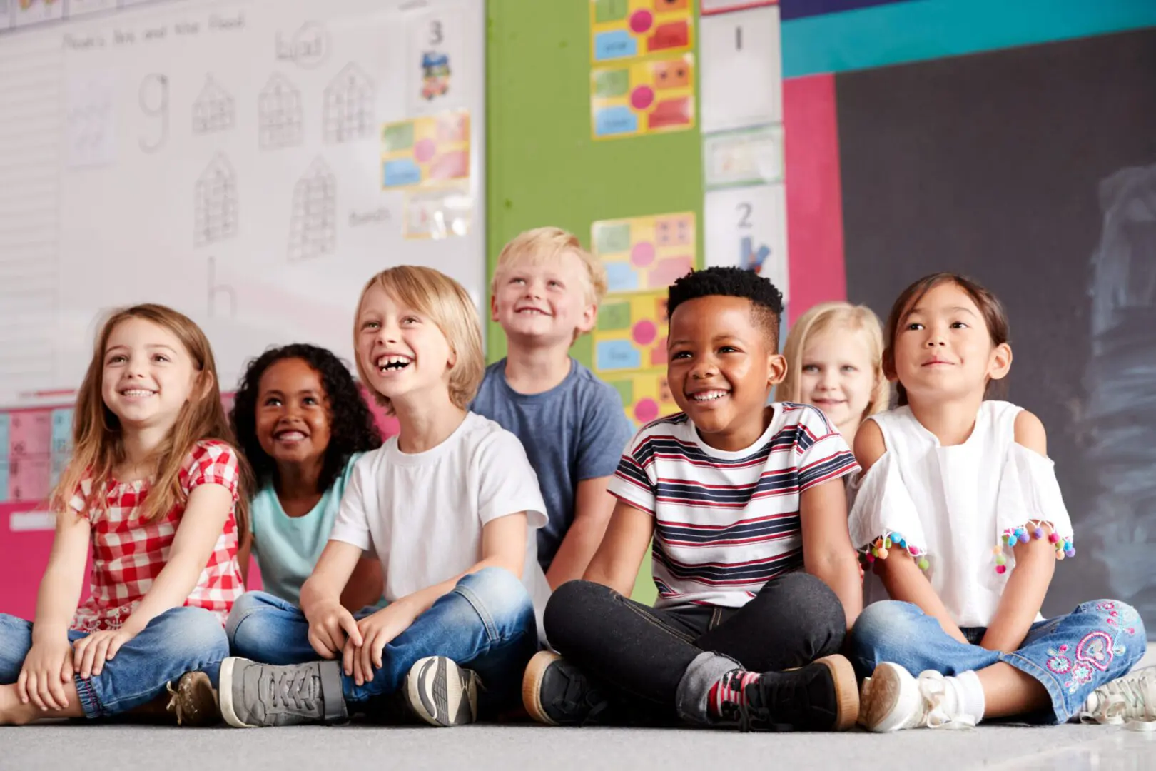 Group Of Elementary School Pupils Sitting On Floor In Classroom